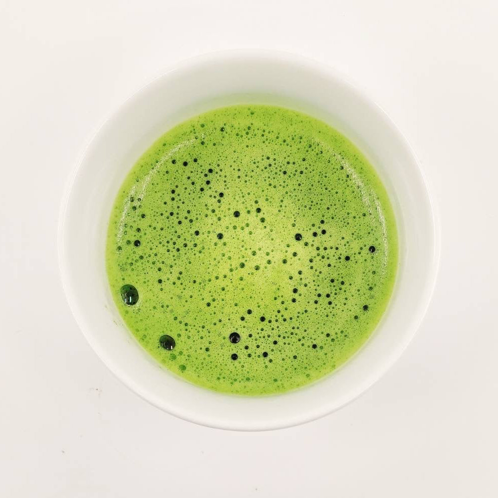 Green smoothie in a white bowl on a light gray background