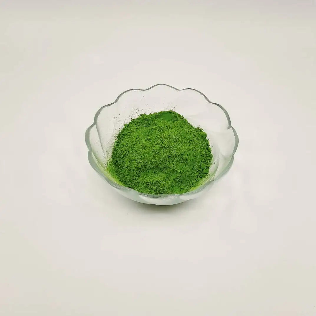 Glass bowl with green powder on a light gray background