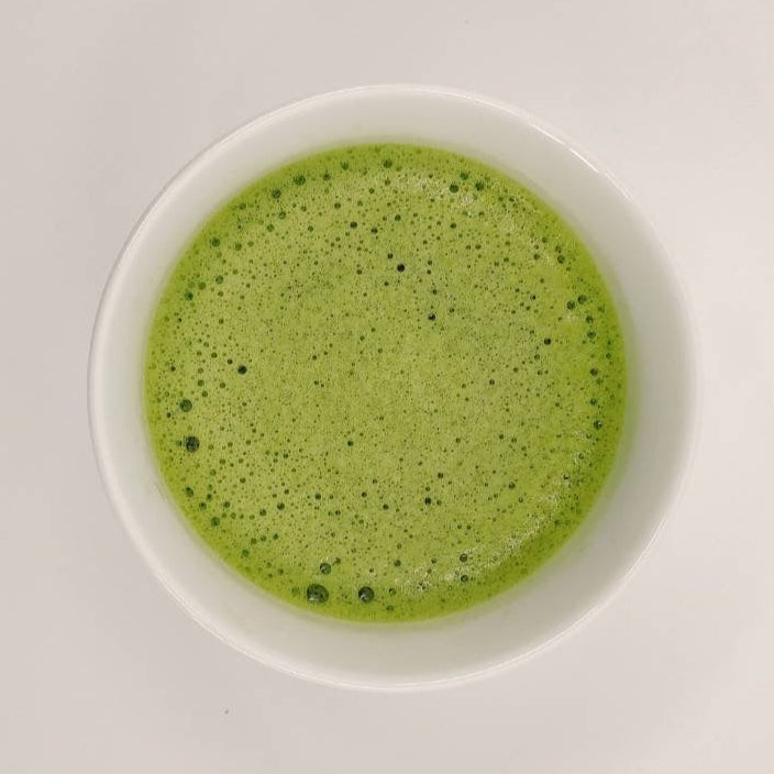 Green smoothie in a white bowl on a light gray background