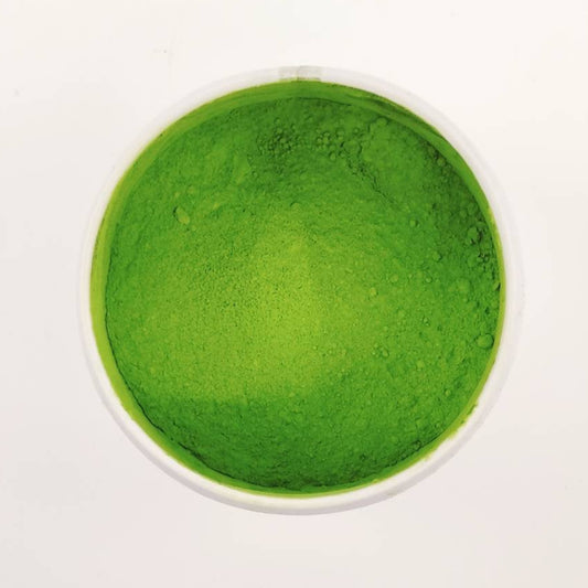 Green powder in a small container on a white background