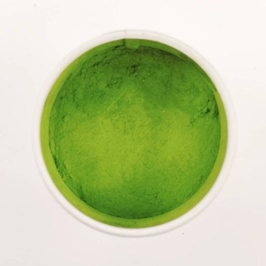 Green powder in a small container on a white background
