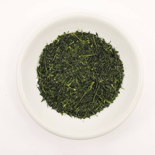 Green tea leaves on a white plate with a white background
