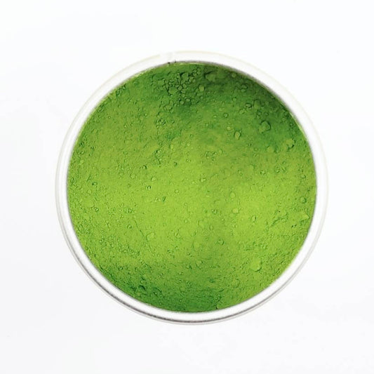 Green powder in a small white container on a white background