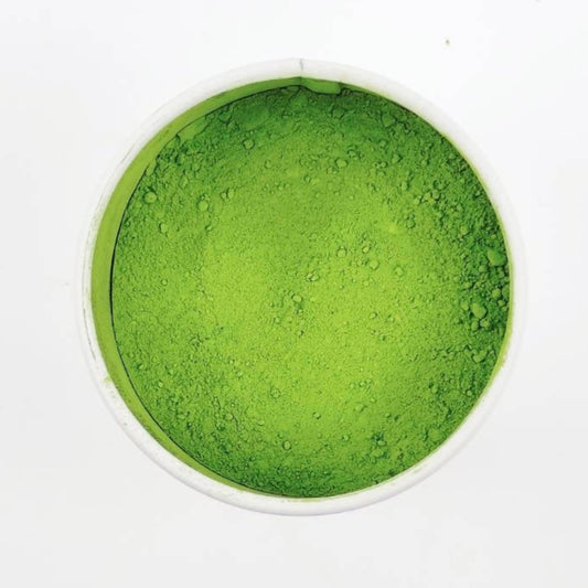 Green powder in a small dish on a white background