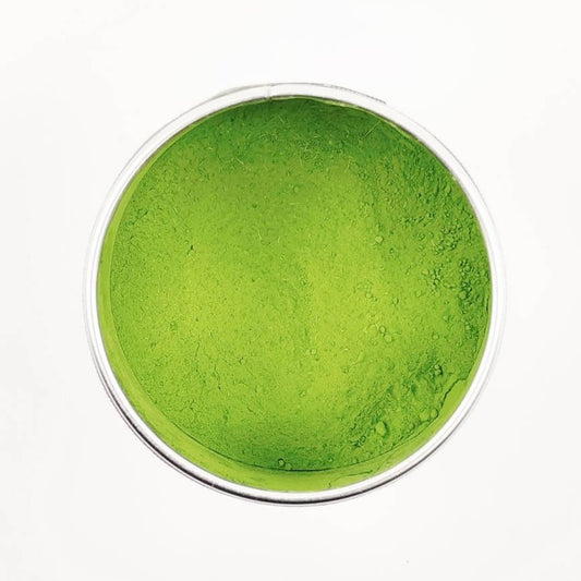 Green powder in a white container on a white background